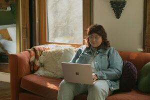 a woman sitting on a couch using a laptop computer